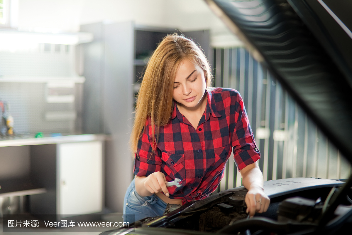 年轻性感的褐发机修工穿着格子衬衫在车库里。